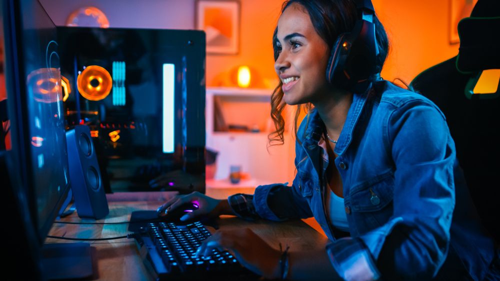 Une joueuse PC souriante qui joue avec un clavier gamer