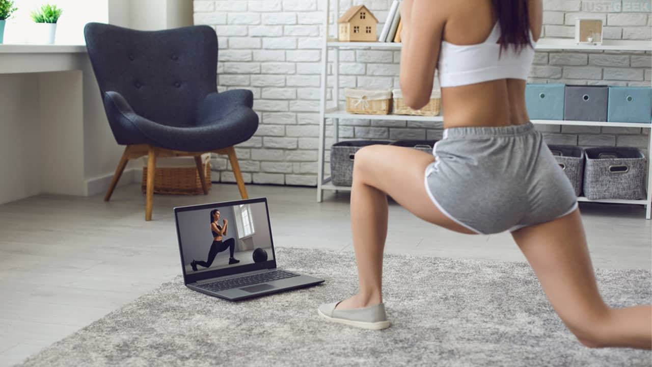 Une jeune femme qui pratique le sport à la maison devant un ordinateur