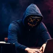 Personne masquée en train de lancer une cyberattaque depuis un ordinateur portable