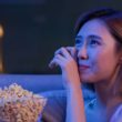 Une jeune femme pleure en regardant un film très émouvant avec du pop-corn la nuit