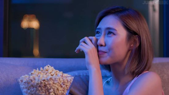 Une jeune femme pleure en regardant un film très émouvant avec du pop-corn la nuit