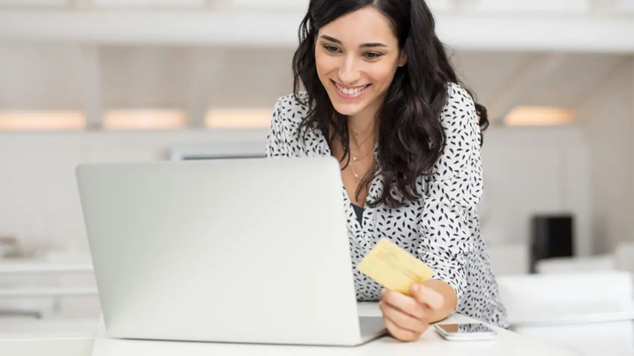 Une jeune femme devant son ordinateur faisant des achats sur Internet