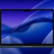 Aperçu du fond d’écran macOS Tahoe 26 en mode sombre affiché sur un MacBook