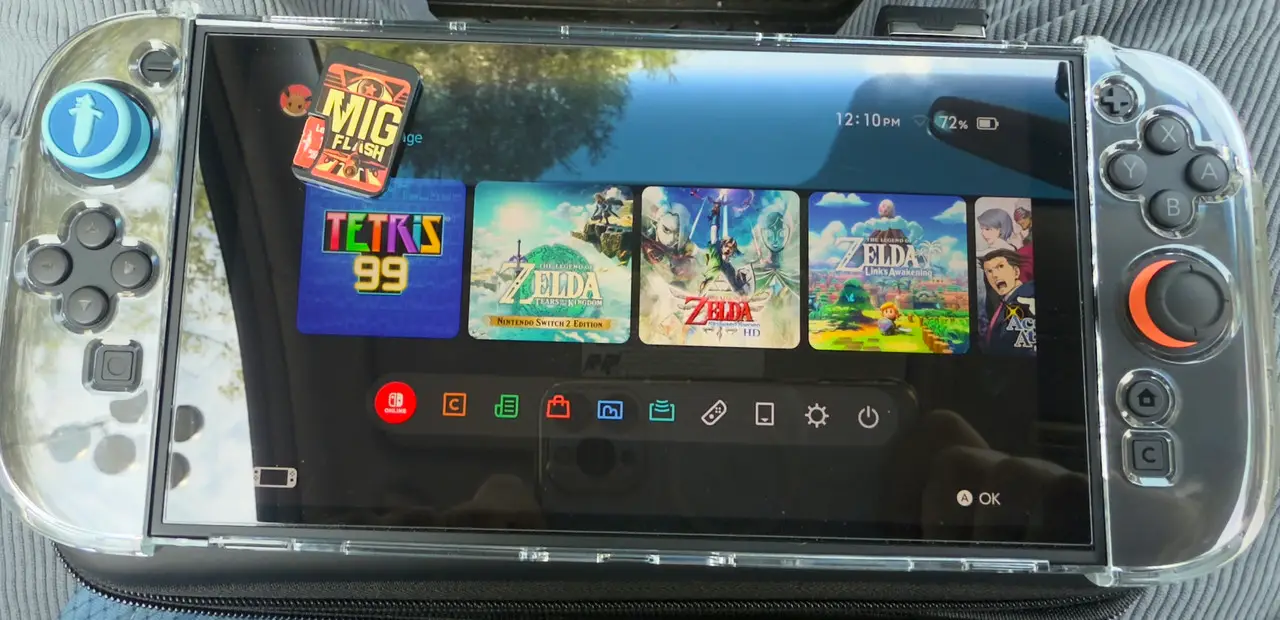 Console Nintendo Switch 2 avec MigFlash inséré, affichant plusieurs jeux comme Tetris 99 et Zelda