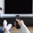 Personne tenant une télécommande face à un téléviseur éteint – changement des chaînes de la TNT le 6 juin 2025