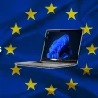 Ordinateur Windows 11 sur fond drapeau européen illustrant les changements imposés par le Digital Markets Act