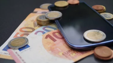 Billets et pièces en euros posés sur un smartphone illustrant le coût des forfaits mobile en France