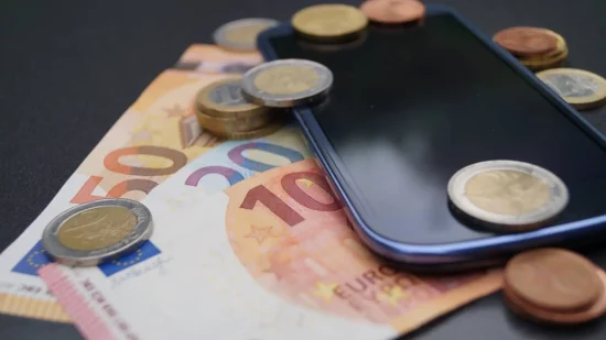 Billets et pièces en euros posés sur un smartphone illustrant le coût des forfaits mobile en France