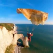 Parapente au-dessus des falaises avec une voile remplacée par une crêpe – image générée par IA dans le style de Veo 3